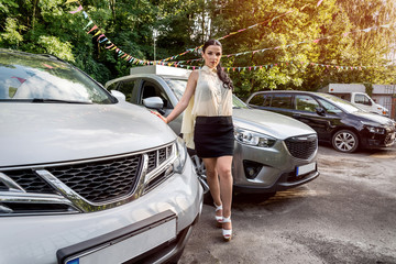 Woman posing near new cars on parking place