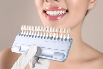 Dentist checking young woman's teeth color, closeup