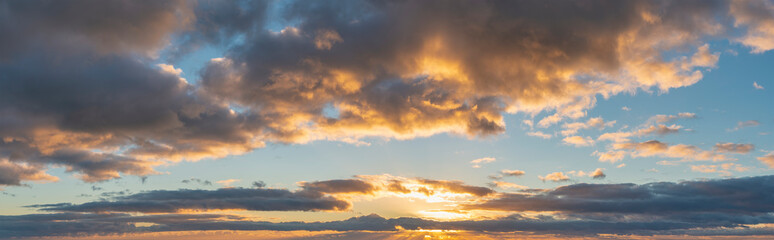 Obraz premium Beautiful colorful vibrant golden hour sunset skyscape with cloud formation and setting sun