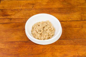 Old Fashioned Oatmeal in white bowl on rustic wood background
