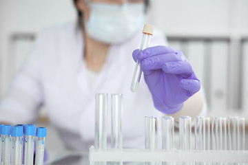 Close-up of professional female scientist in protective eyeglasses making experiment with reagents...