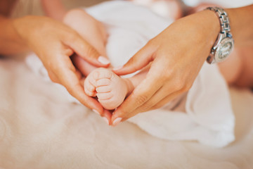 Mom holds children's legs in her arms. Happy family concept, love,caring. Baby feet in mother hands. Newborn
