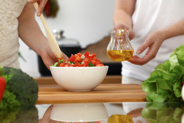 Closeup of human hands cooking in kitchen. Mother and daughter or two female friends cutting vegetables for fresh salad. Friendship, family dinner and lifestyle concepts