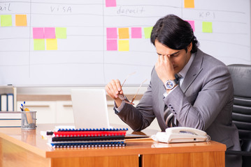 Young handsome employee working in the office