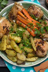 Baked chicken legs with potatoes and carrots under spices and seasonings