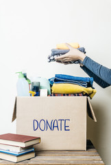 CLOTHES DONATION AND FOOD DONATION CONCEPT. A woman holding a donation box with clothes, shoes and...