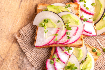 Delicious wheat toasts with radish, avocado and sprouts