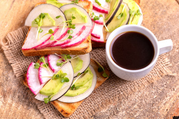 Delicious wheat toasts with radish, avocado and sprouts