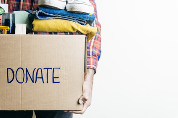 CLOTHES DONATION AND FOOD DONATION CONCEPT. A man holding a donation box with clothes, shoes and...