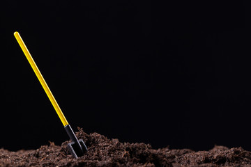 Shovel with a yellow handle stuck in the ground.