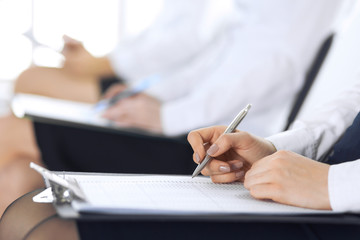 Business people taking part at conference or training at office, close-up. Women sitting on chairs and making notes like at queue or meeting 