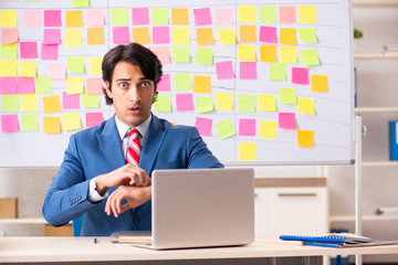Young handsome employee with many conflicting priorities 