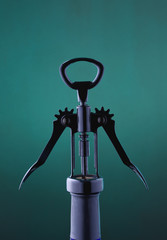 Glass blue bottle with a corkscrew in a dark key on a colored background. A bottle of wine.