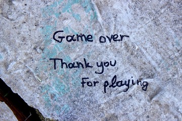 Handwritten message on a big stone at forest of an unfulfilled love of a couple in love "game over thank you for playing"