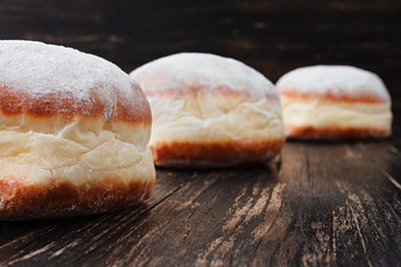 Freshly made doughnuts filled with jam and covered in powdered sugar on a rustic wooden table