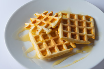 Viennese, Belgian waffles with honey on a white plate. Selective focus.