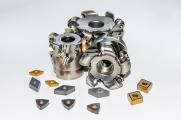 Two undamaged and one damaged indexable milling cutter for CNC milling machine with four types of carbide inserts with selective focus isolated on white