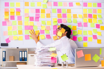 Young employee in conflicting priorities concept 