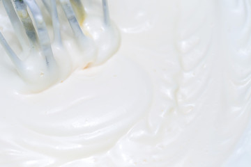 Fototapeta na wymiar Mixing white egg cream in a bowl with a motor mixer, baking cake