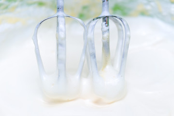 Mixing white egg cream in a bowl with a motor mixer, baking cake
