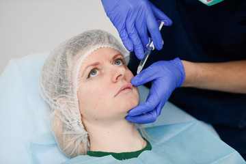 Naklejka premium girl do plastic operation in medical clinic; doctor does lip augmentation surgery; injecting operation on lips