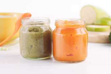 Broccoli and pumpkin vegetable puree in jars on white wooden background near ingredients