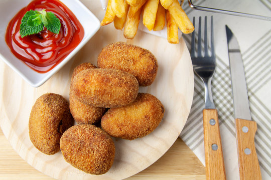 Upper view ham and chicken croquettes on a wood plate with tomate and chips