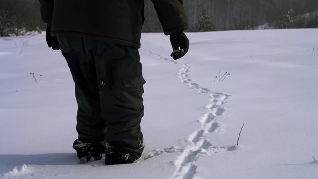 Man going through deep snow next to traces of animals - (4K)