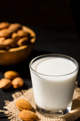 Almonds milk in wooden bowls on black background