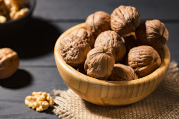 Nuts with shell in wooden bowls on slate background