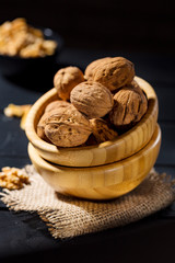 Nuts with shell in wooden bowls on slate background