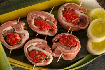 raw meat rolls on skewers, on green leaves, close-up
