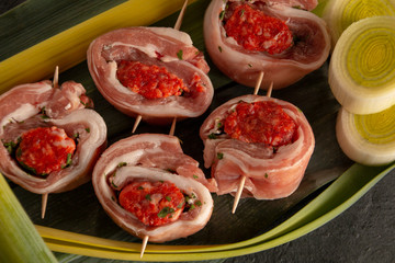 raw meat rolls on skewers, on green leaves, close-up