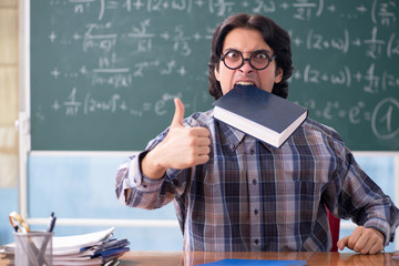 Young funny math teacher in front of chalkboard 