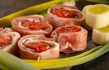 raw meat rolls on skewers, on green leaves, close-up