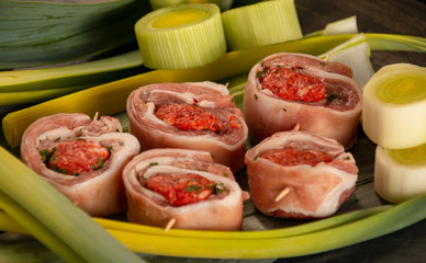 raw meat rolls on skewers, on green leaves, close-up