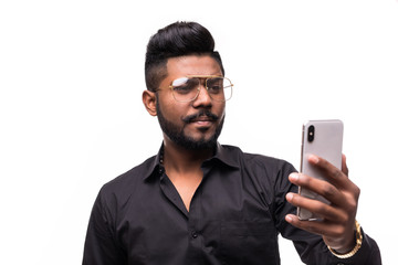 Hipster indian young man with beard and mustache busy using smartphone, isolated over white background