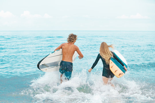 Surfers at the beach- Smiling couple of surfers swiming and having fun in summer. Extreme sport and vacation concept