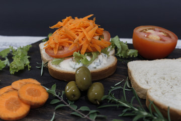 Healthy vegetarian sandwich with carrot, Tomato, lettuce and spices, served on an wooden board.