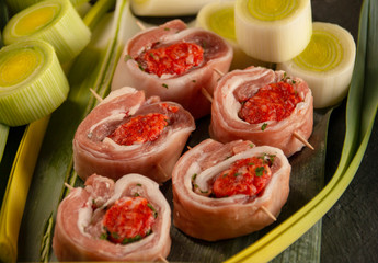 raw meat rolls on skewers, on green leaves, close-up