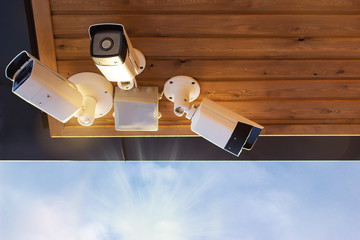 Security cameras under the roof with buildings and sky background © Roman
