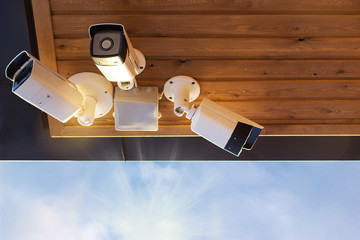Security cameras under the roof with buildings and sky background