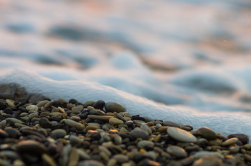 pebble stones on the sea beach, the rolling waves of the sea with foam