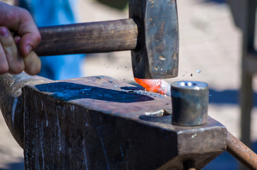 blacksmith performs the forging of hot glowing metal on the anvil