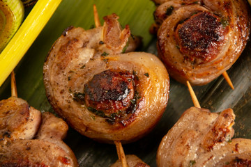 fried meat rolls on skewers, on green leaves, close-up