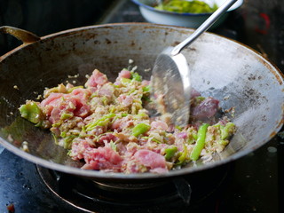 Cooking pork stir fried with Thai chili paste in a hot wok at home