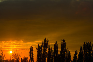 Landscape with dramatic light - beautiful golden sunset with saturated sky and clouds.