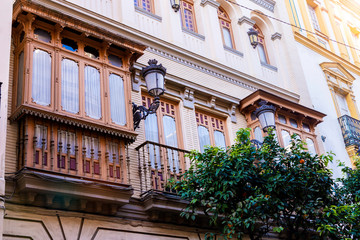 Traditional facades of houses with beautiful carved wooden balconies of the city of Seville, Andalusia, Spain.