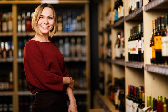 Photo of happy blonde woman in store with wine