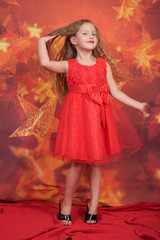 pretty cute caucasian child girl in red evening dress and mother's high heels standing on orange...